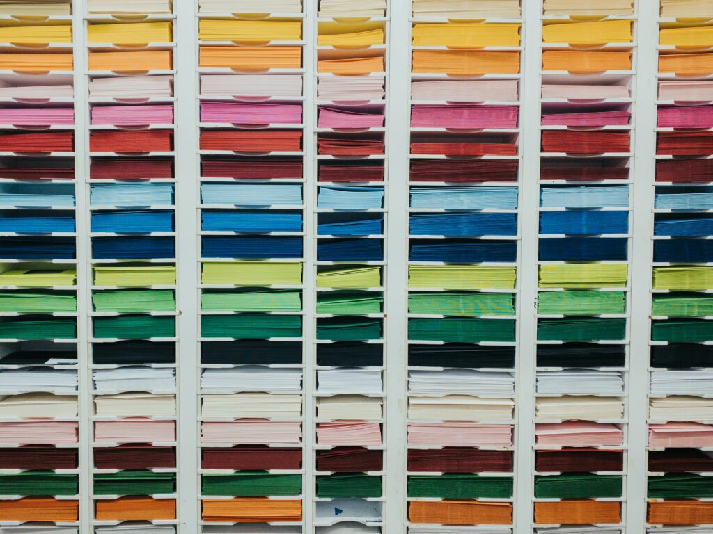 A photograph of many colored papers precisely organized into a shelving unit.